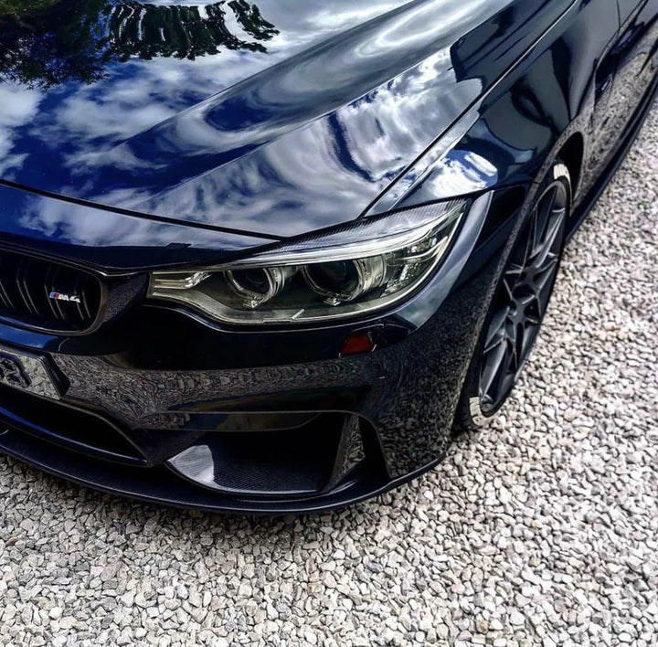Carbon fibre headlight eyebrow covers fitted to a BMW M4 F82, front three-quarter view