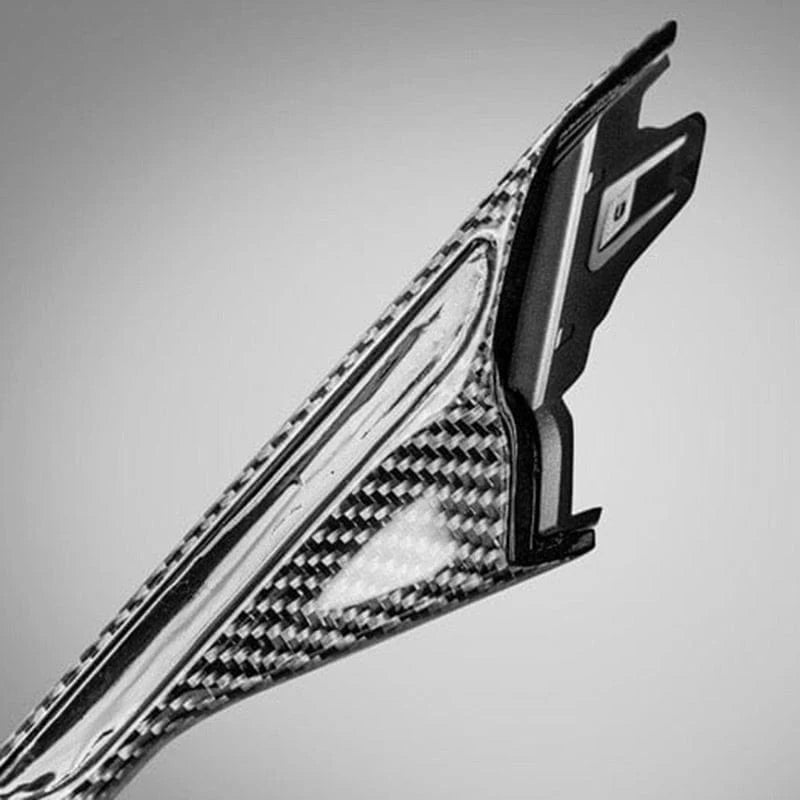 Pair of dry carbon fibre fender trims for BMW M5 F90 on a plain background